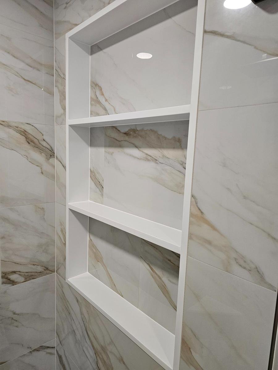 Built-in shower niche detail Inverness IL — recessed niche with matched marble tile and chrome shelf