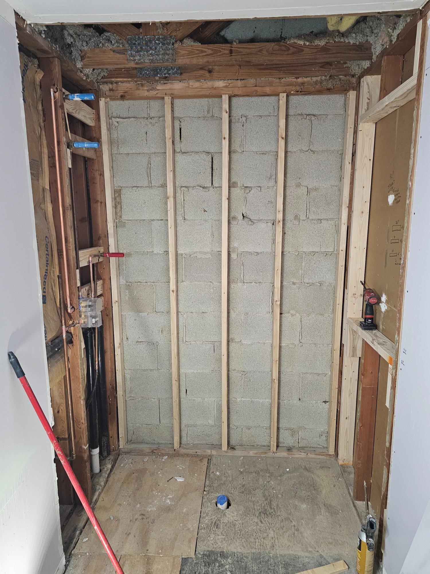 Demo complete — studs and concrete block exposed, new copper plumbing rough-in