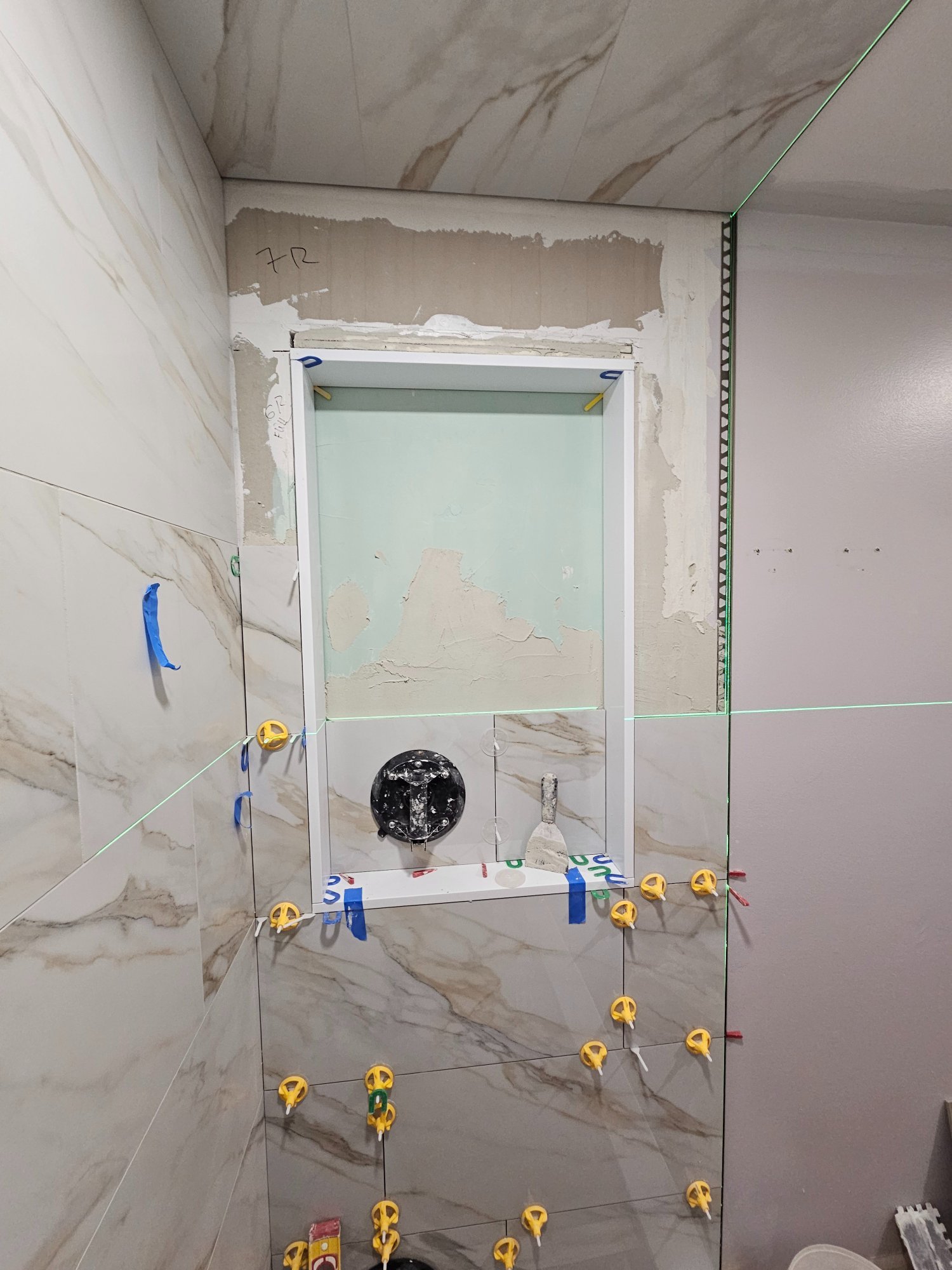 Calacatta wall tile going up with laser level, niche in progress — Inverness IL